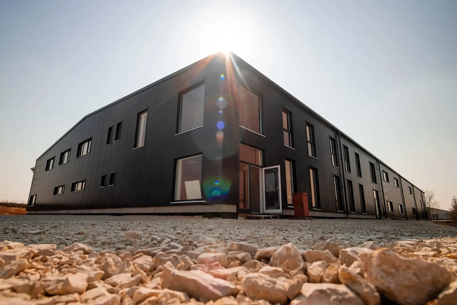 Anthrazitfarbene Stahlhalle der Metz GmbH in Kümmersbruck im Gegenlicht