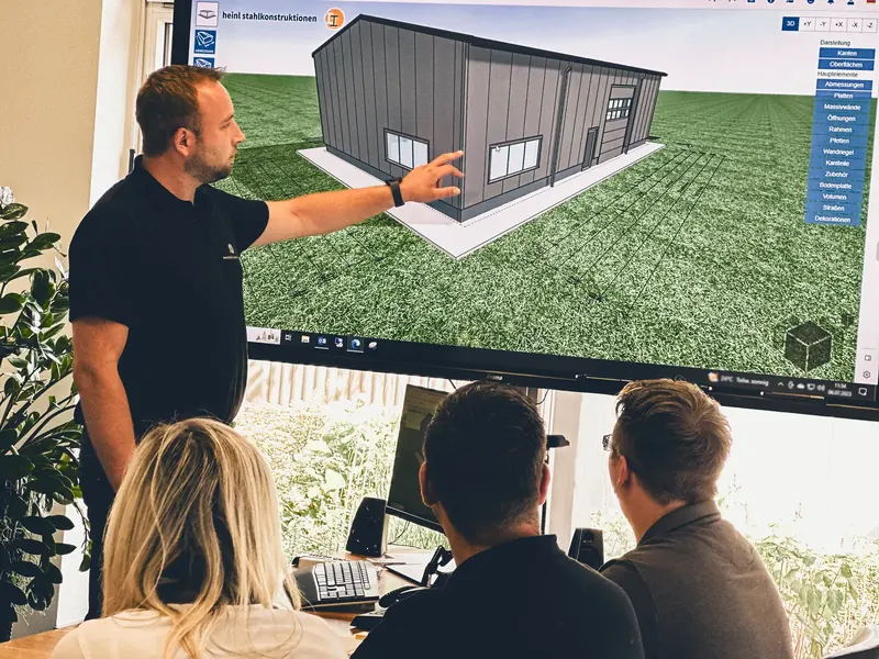 Besprechung einer Stahlhalle am 3D-Modell auf dem Bildschirm